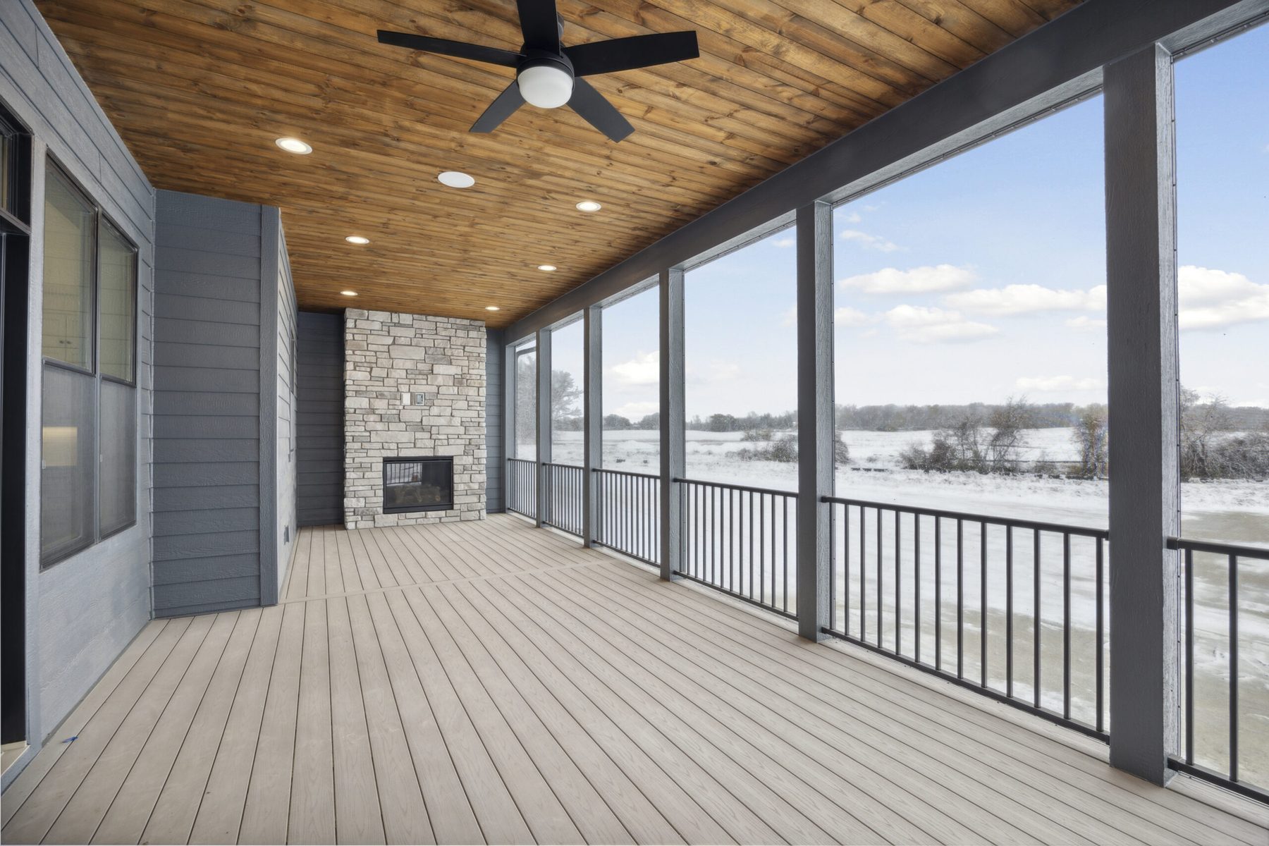Covered deck with a stone fireplace overlooking the prairie — The Dwelling
