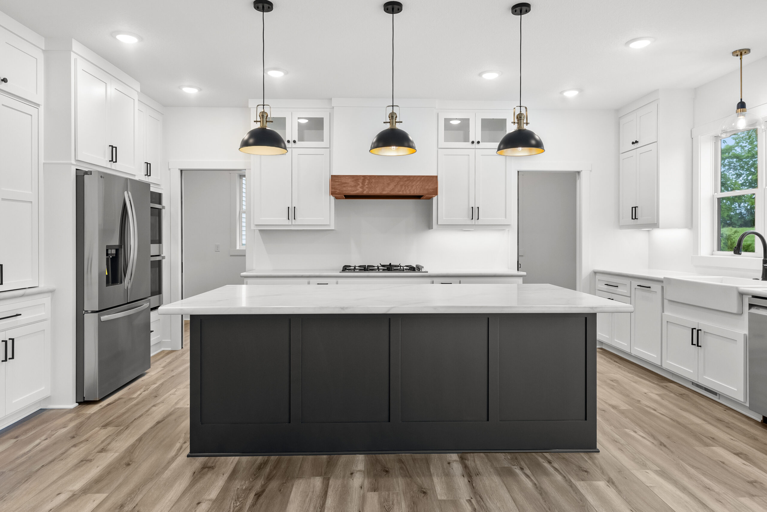 White kitchen with an oversized black island and black pendants — The Homestead