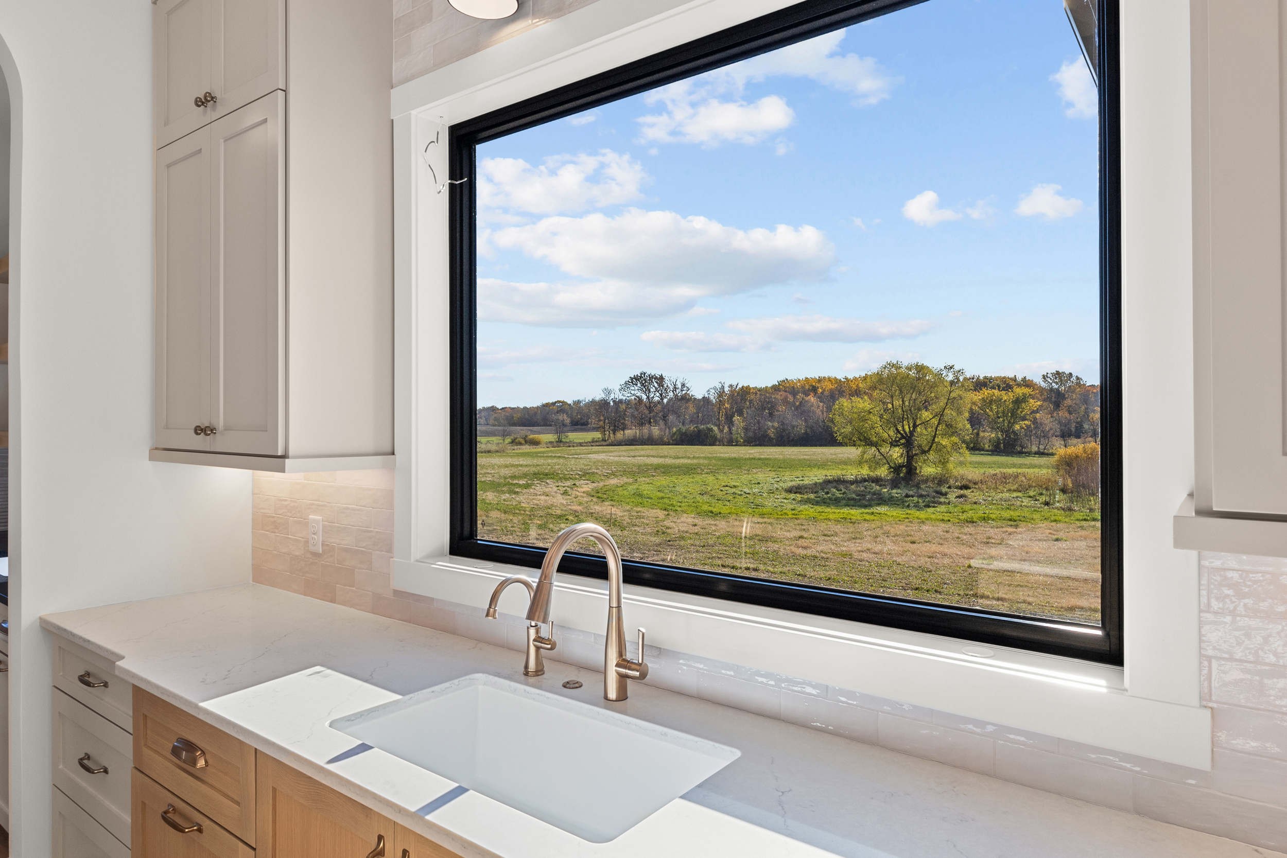 Kitchen picture window framing open prairie — The Horizon