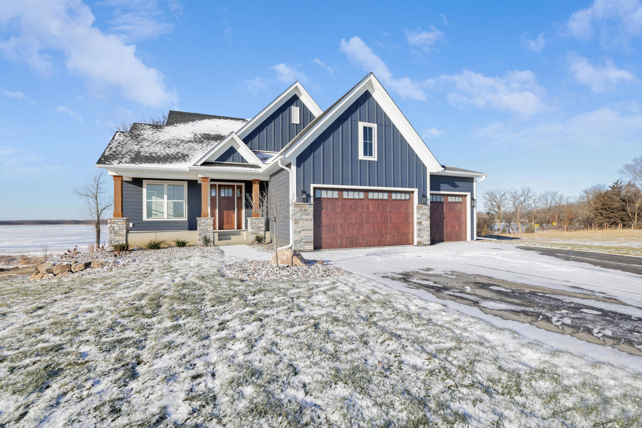 Navy craftsman rambler exterior with stone and a covered porch — The Model