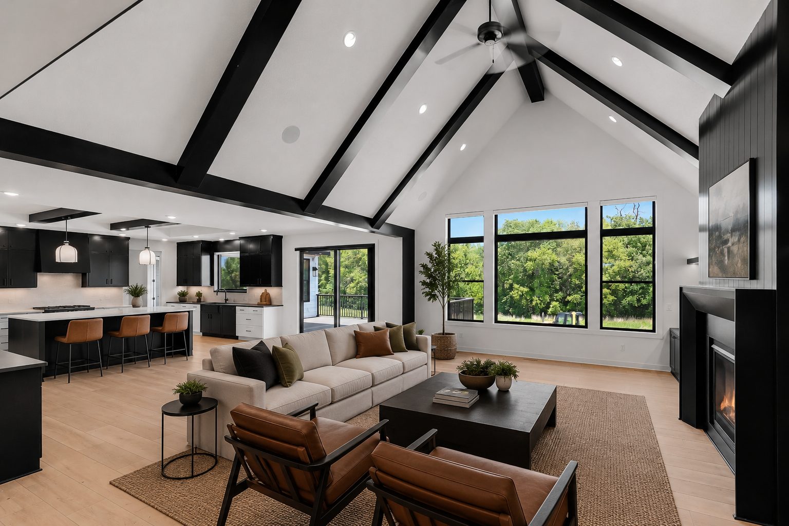 Vaulted great room with black-stained beams, open kitchen and fireplace inside The Noir