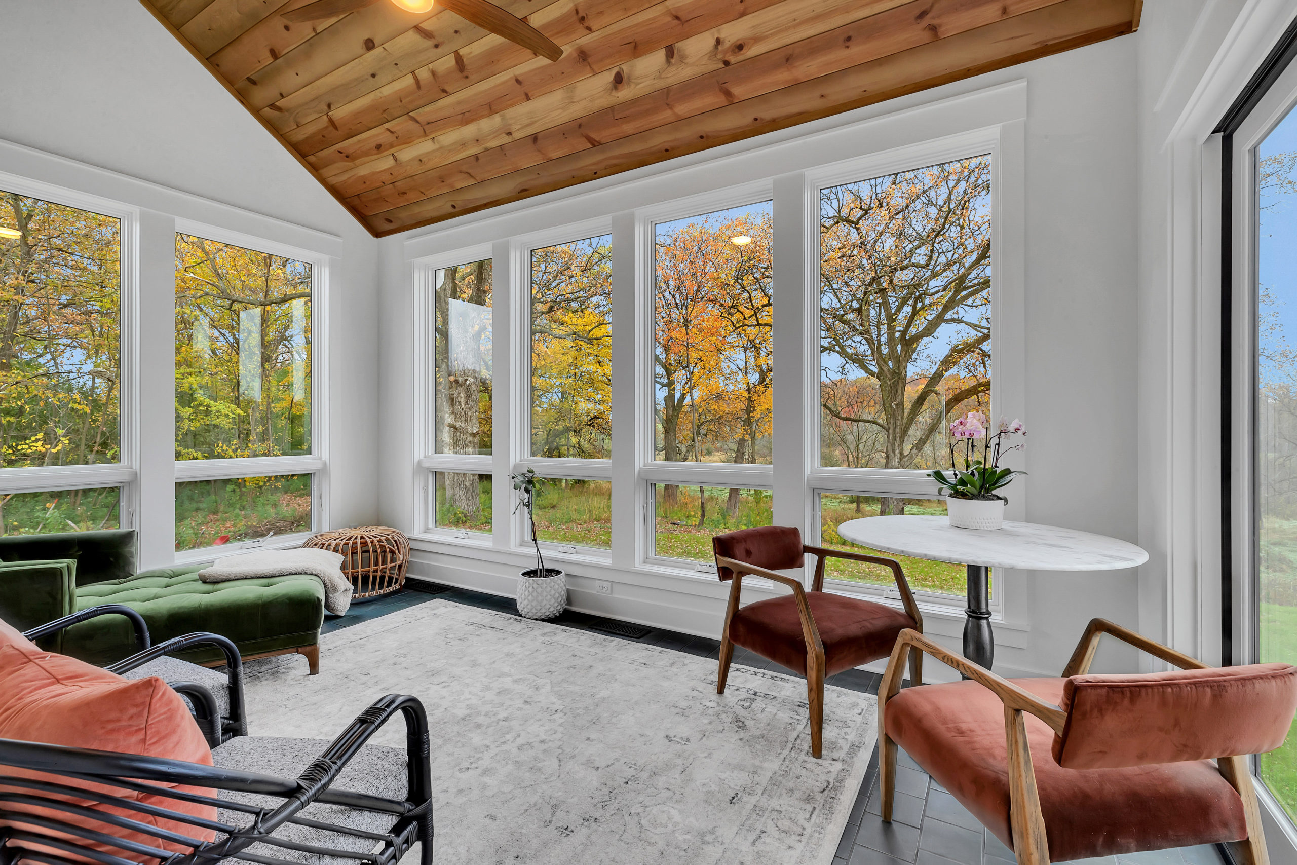 Cedar-ceilinged four-season porch framing autumn woodland views