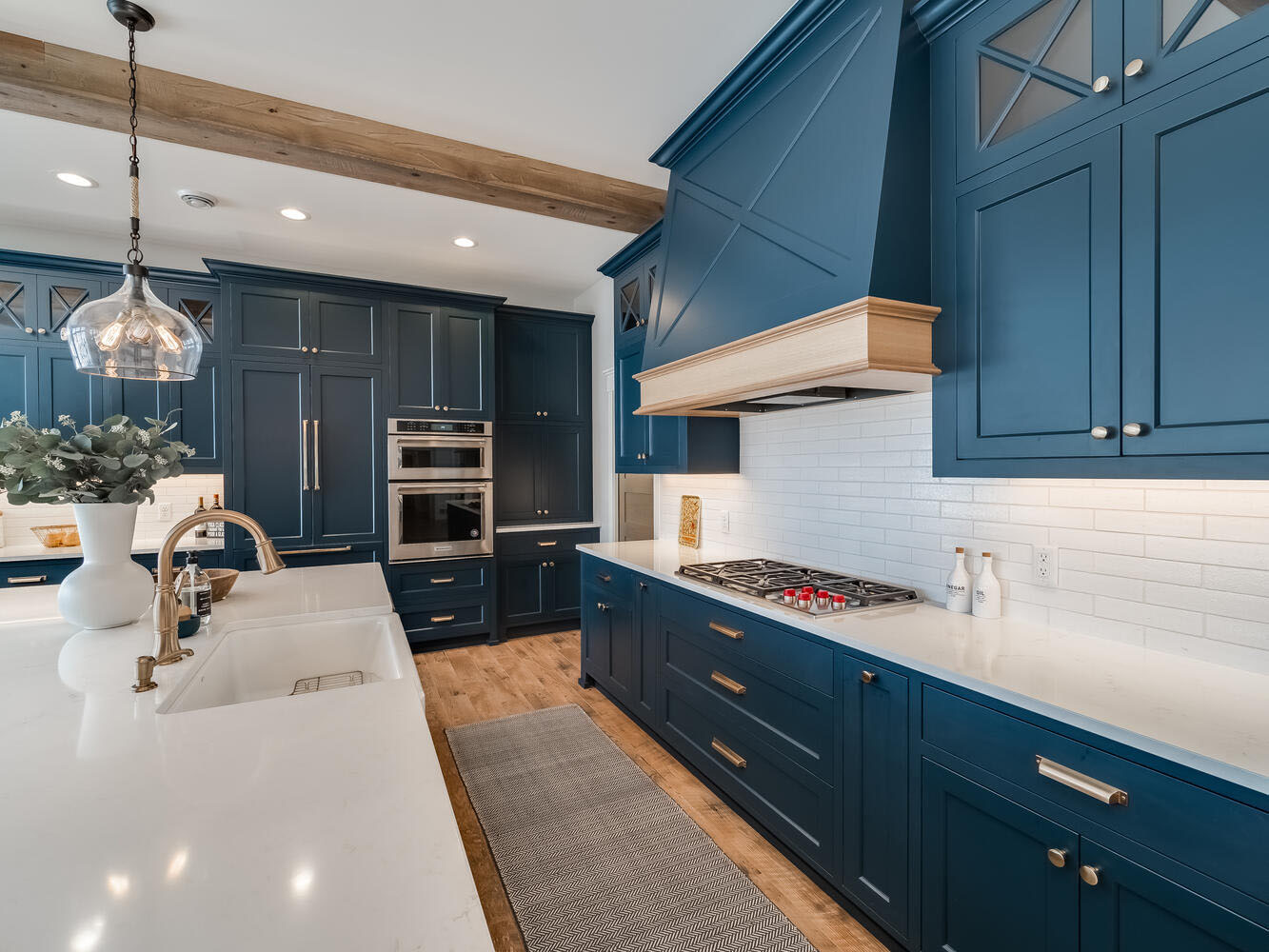 Navy custom kitchen with reclaimed-wood beam, white quartz and brass fixtures