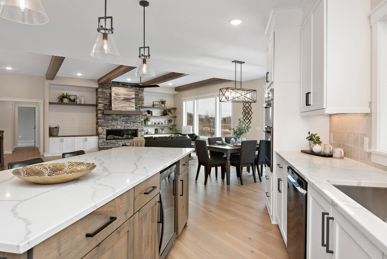 Light-filled kitchen and dining opening to a great room with a stone fireplace